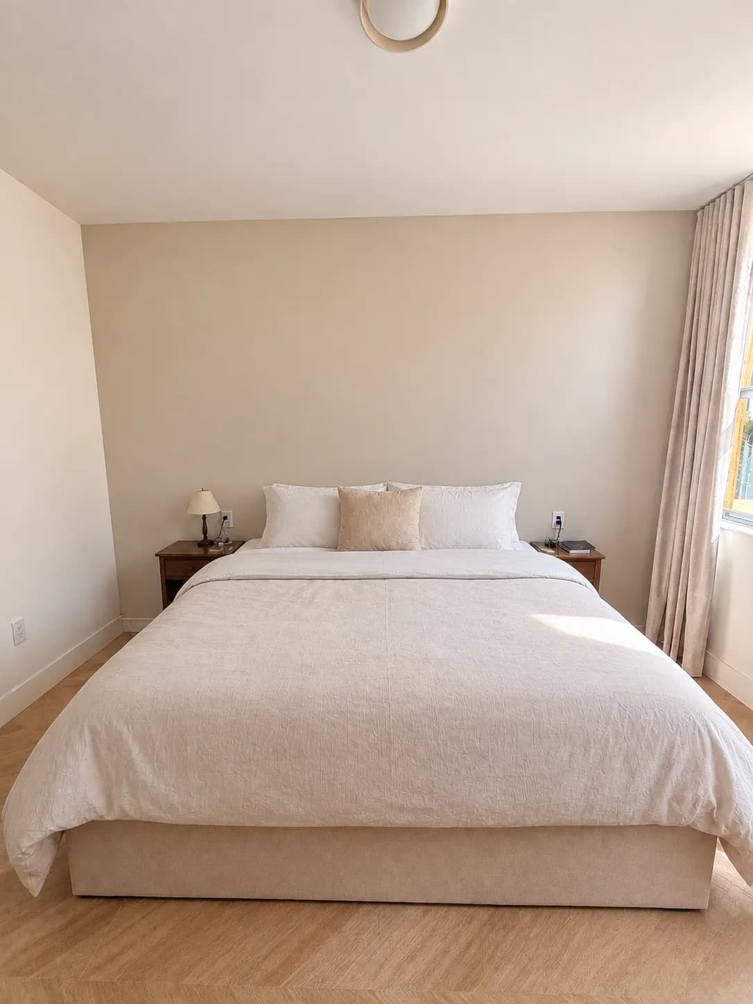 El dormitorio antes: la cama contra una pared beige lisa, con dos mesitas de madera y sin ningún mueble empotrado