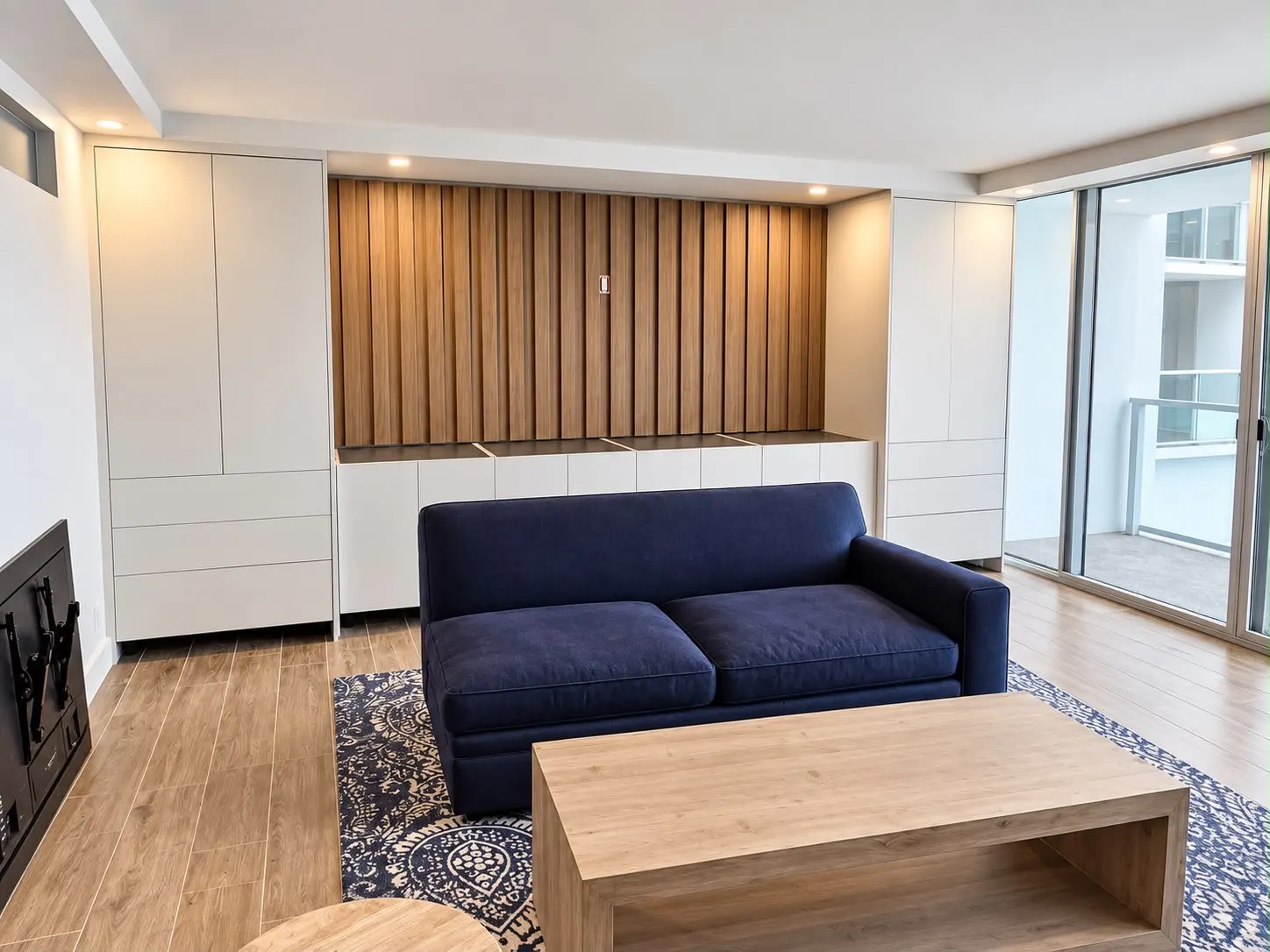 Pared de sala con empotrados blancos a los lados de un panel acanalado de roble y una consola baja